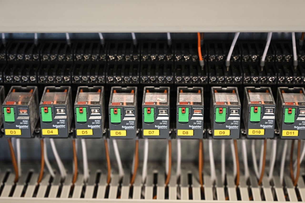 why-choose-us-01 Close-up view of electrical relays in an industrial panel box showcasing circuit components.
